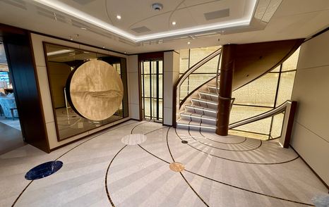 Main deck lobby on the Amels 242 Casino Royale with curved staircase and decorative marble floor.