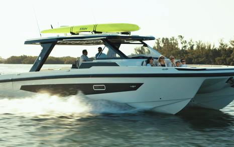 Aquila 45 Sport powercat underway side profile with hardtop and roof-mounted paddleboards, showing twin-hull design and open cockpit layout