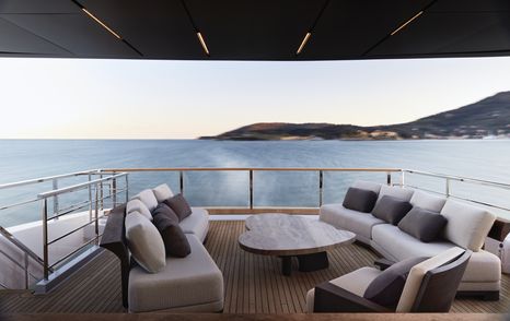 Exterior lounge area on upper deck of Sanlorenzo 44 Alloy. Sofas facing over a low coffee table, surrounded by sea.