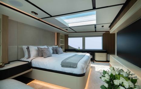 Master cabin onboard the Majesty 111. Central berth facing starboard with wide window in background.