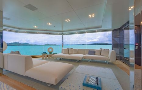 Upper lounge area in the upper salon onboard superyacht WANDERLUST. Cream seating surrounds a low coffee table with the whole area walled by unbroken wall of glazing. 