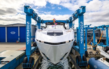 Frontal view of Sunseeker 100 Yacht being lowered in to water. Sunseeker facility visible in background.