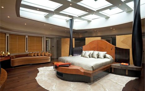 Master cabin onboard superyacht AV, central berth with sofa in background and huge sunroof directly above bed.