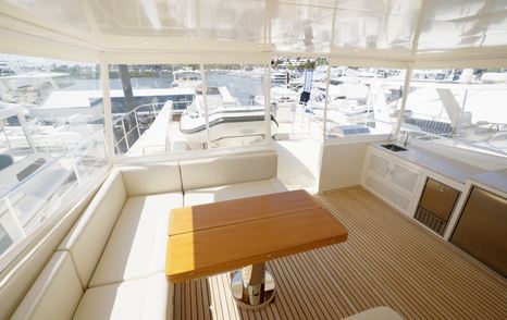 Fleming 85 flybridge lounge and dining space with wraparound seating and wet bar