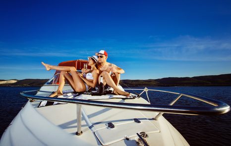 Couple sitting on yacht with beautiful blue sky behind