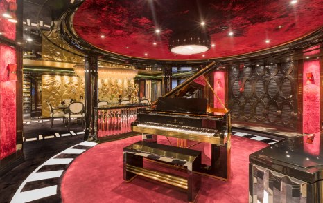 Lurssen yacht PHOENIX 2 highly stylized room in black and white with deep crimson; grand piano with heavy gilt edging is central in the room shot 