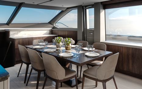 Interior dining option onboard the Sunseeker Ocean 182. Dining table surrounded by eight chairs and large windows on all sides.