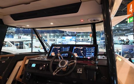 Wide view of the Aiata Sunfinder 50 helm station with steering wheel, dual screens and enclosed windscreen.