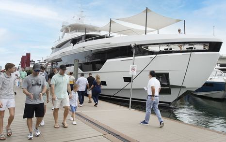 A superyacht berthed at the Miami International Boat Show with visitors walking past