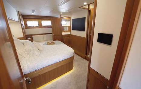 Fleming 85 master suite featuring island double berth, TV, control panel and private living space
