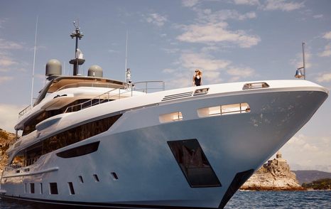 Front of Benetti Diamond 145 INK superyacht from angle with sea, sky and cliffs in background