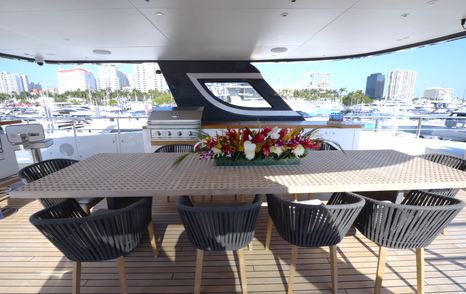 Benetti Oasis 34M sundeck dining table beneath the hardtop, providing sheltered alfresco dining for guests.