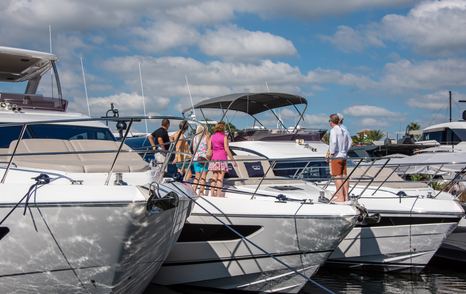 Motor yachts for sale berthed at FLIBS with visitors exploring the bows