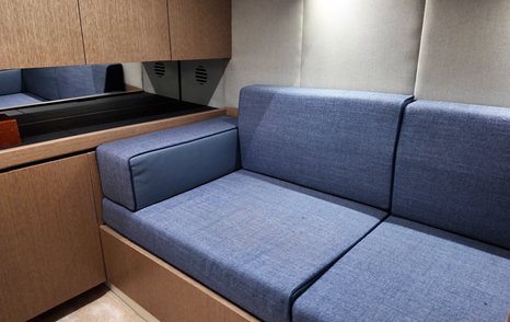 Compact sofa in the amidships cabin of the Aiata Sunfinder 50, set against wood cabinetry and neutral wall panels.