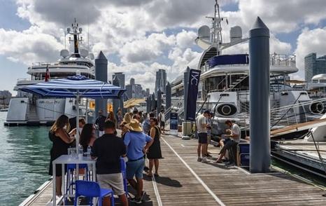 Ground-level view of Superyacht Miami with visitors walking along pontoon to berthed superyachts