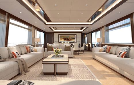 Long image of Damen SeaXplorer 55 yacht living area on main deck, grey sofas along port and starboard sides, coffee table and patterned rug in centre