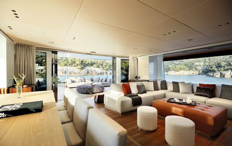 Overview of Benetti Oasis 40 Salon and formal dining area, with wide stretching windows on all sides and open sliding doors aft.