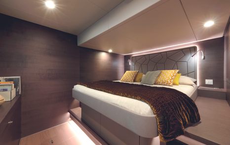 The owner's cabin features a central bed, mood lighting and warm brown and cream tones