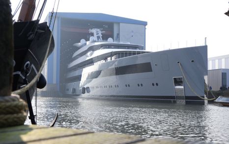 Frontal view of Feadship MOONRISE leaving the docks, surrounded by construction yard and sea