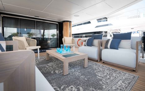 Exterior seating situated on aft main deck of Majesty 111. Large armchairs with blue cushions surround a coffee table.