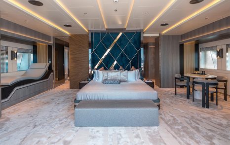 Large cabin on superyacht TATIANA with bed and table and chairs visible