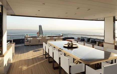 Dining area onboard Project Rinascimento, long 12 seater table overlooking sea views aft.