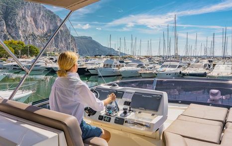 female at helm of motor yacht in marina