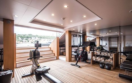 Gym onboard YXT 24 Evolution, exercise equipment in centre and round edges of room, open doorway with steps leading to swim platform