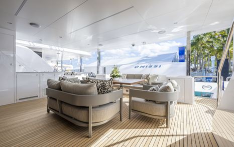 Overview of the aft deck onboard superyacht ISSIMO, neutral coloured seating facing in with transom door lifted open.