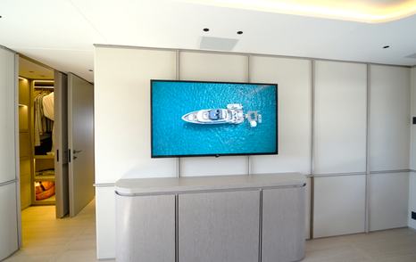 Benetti Oasis 34M owner's suite lounge and entertainment area with television and walk-in wardrobe access.