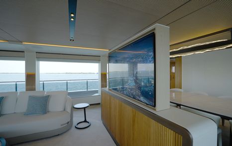 65-inch pop-up television dividing the lounge and dining areas aboard the Gulf Craft Majesty 145