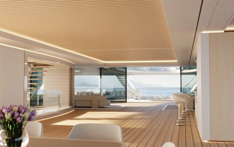 Overview of interiors onboard Feadship concept PURE. Wet bar to starboard with interior dining table in foreground. Open doors aft with exterior deck space visible.