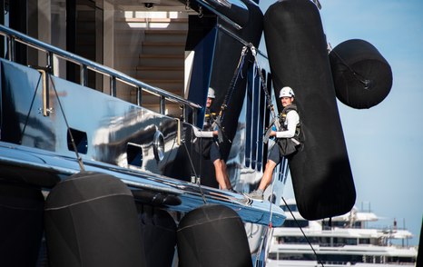 Man harnessed to the side of a motor yacht at the Monaco Yacht Show