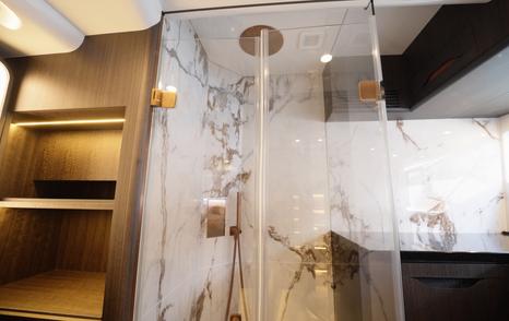 Galeon 520 Fly owner’s bathroom with glass shower enclosure and marble-style wall finish