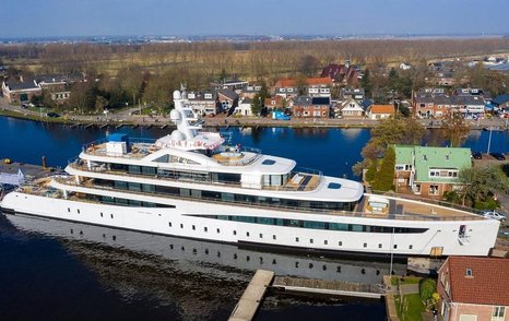 Superyacht VIVA docked, surrounded by local infrastructure and countryside in the background.