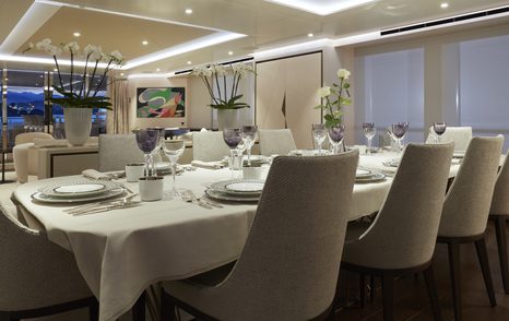 Dining area onboard Heesen 'Project Triton', dining table with eight seats, adjacent to stretch of windows