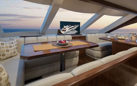 Lounge area/dinette on bridge deck of Viking 75 MY. Table surrounded by abundant windows and diner style wraparound seating.