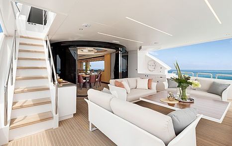 Horizon TO-KALON aft deck, seating area with three facing sofas, overlooking entrance to interiors and staircase on port side