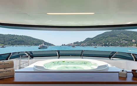 Spacious Jacuzzi onboard Sanlorenzo Lady Lena, overlooking panoramic views of elevated terrain and anchored yachts