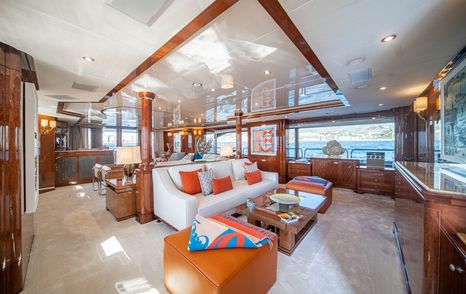 Superyacht Checkmate main saloon with white furniture and coffee table and mounted TV