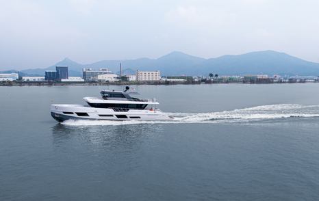 Port side view of CLX96 underway, passing land and infrastructure in background.