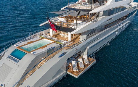 Superyacht TATIANA aft decks, infinity pool and fold down balcony visible, along with alfresco dining options. Surrounded by sea.