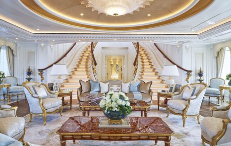 Main salon onboard ALAIYA (TIS). Ornamental seating surrounds coffee table with staircases ascending in background.