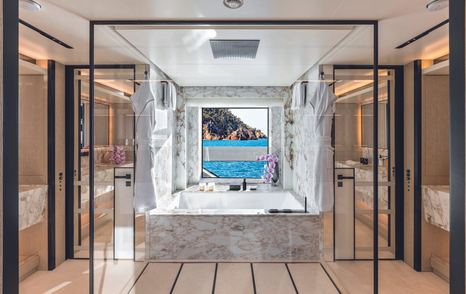 Owner's private bathroom onboard CRN RIO superyacht. Central square bath overlooking large window in background.