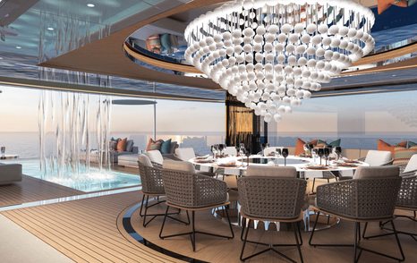 Interior view of Fincantieri Yachts BLANCHE beach area, with dining table in foreground and a waterfall cascading in to swimming pool