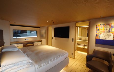 Custom Line Navetta 38 owner’s cabin showing bed, TV wall and ensuite bathroom access forward