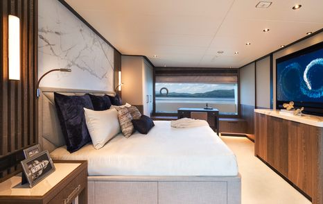 Master cabin onboard Horizon FD110 Tri-deck. Central berth with large window in background.