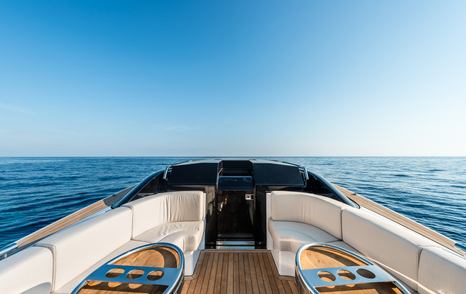 Wooden decking with cream sofas either side of boat, looking towards dark sunken deckhouse