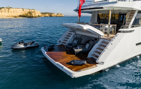 Overview of swim platform onboard the Sunseeker 100 Yacht. Jet Ski sat in water alongside yacht with sunloungers and water toys visible on platform.