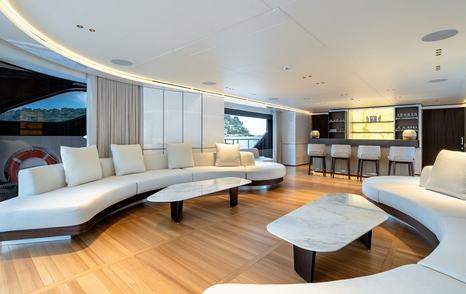 Superyacht Contigo's main saloon with curved sofa and bar area